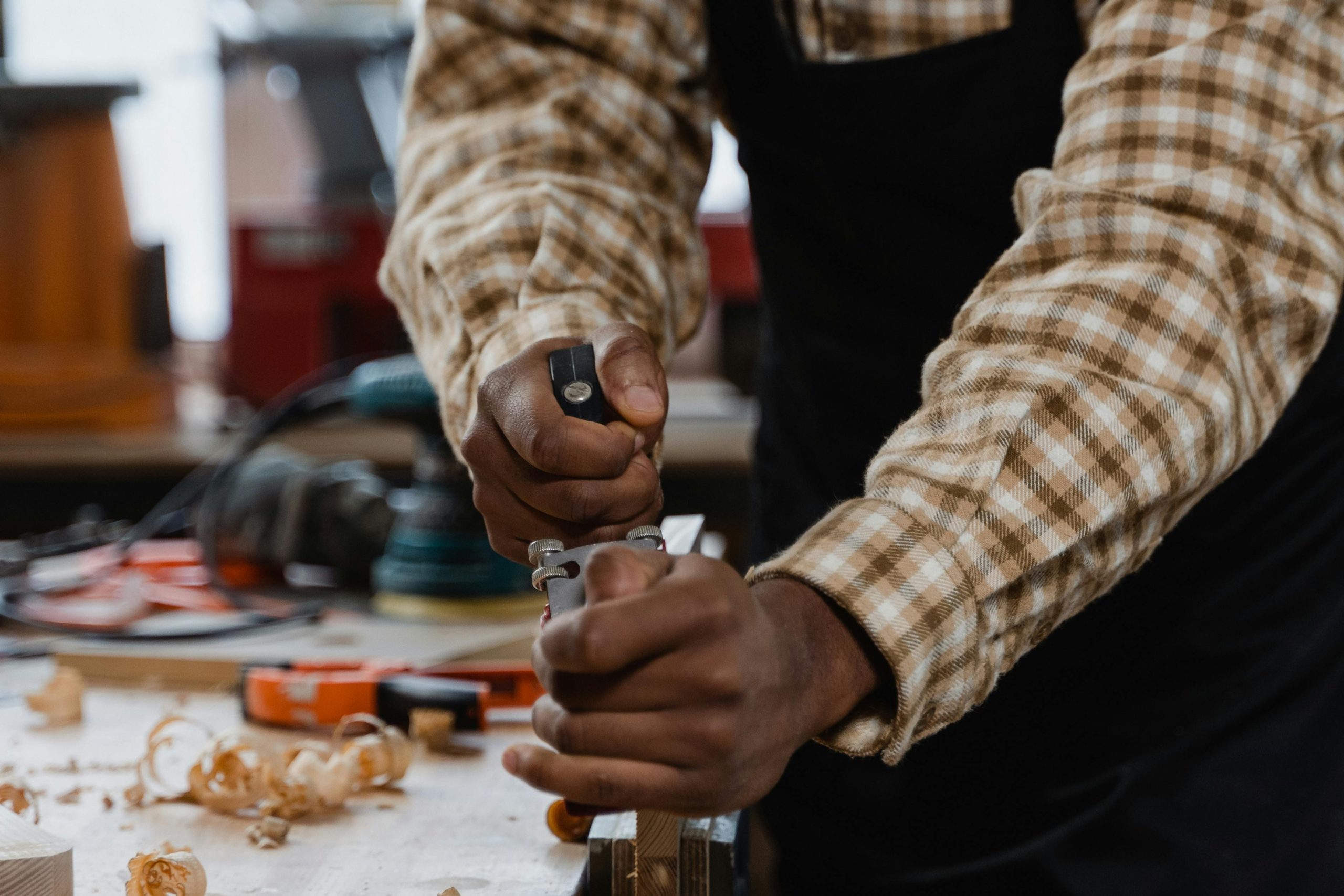 A craftsman skillfully using a hand plane on wood in a woodworking workshop.